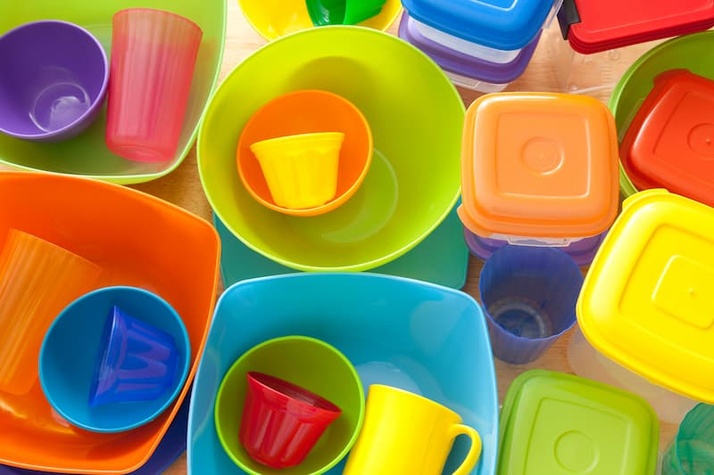 A variety of colorful plastic bowls, cups, and containers arranged on a surface.