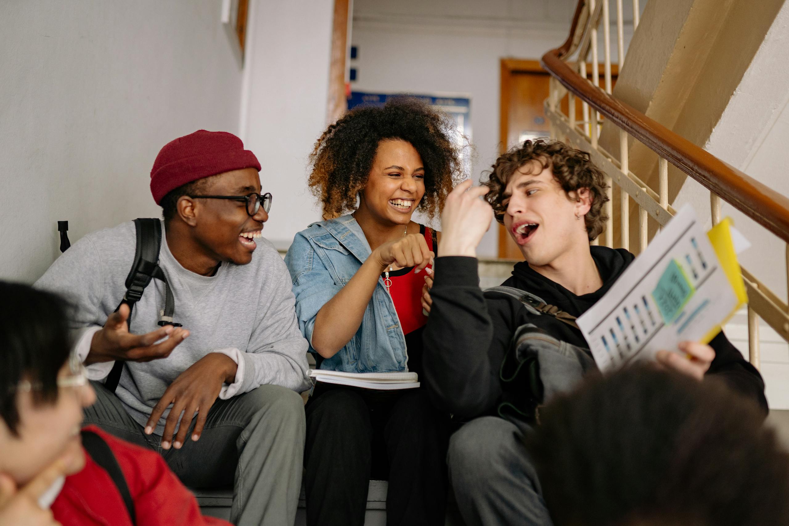 Happy group of diverse students laughing and bonding on campus stairs.